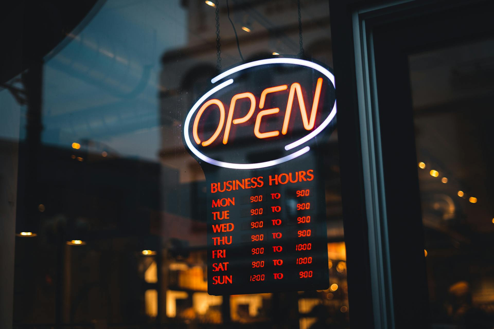 An open sign on a store, with the hours of operation.