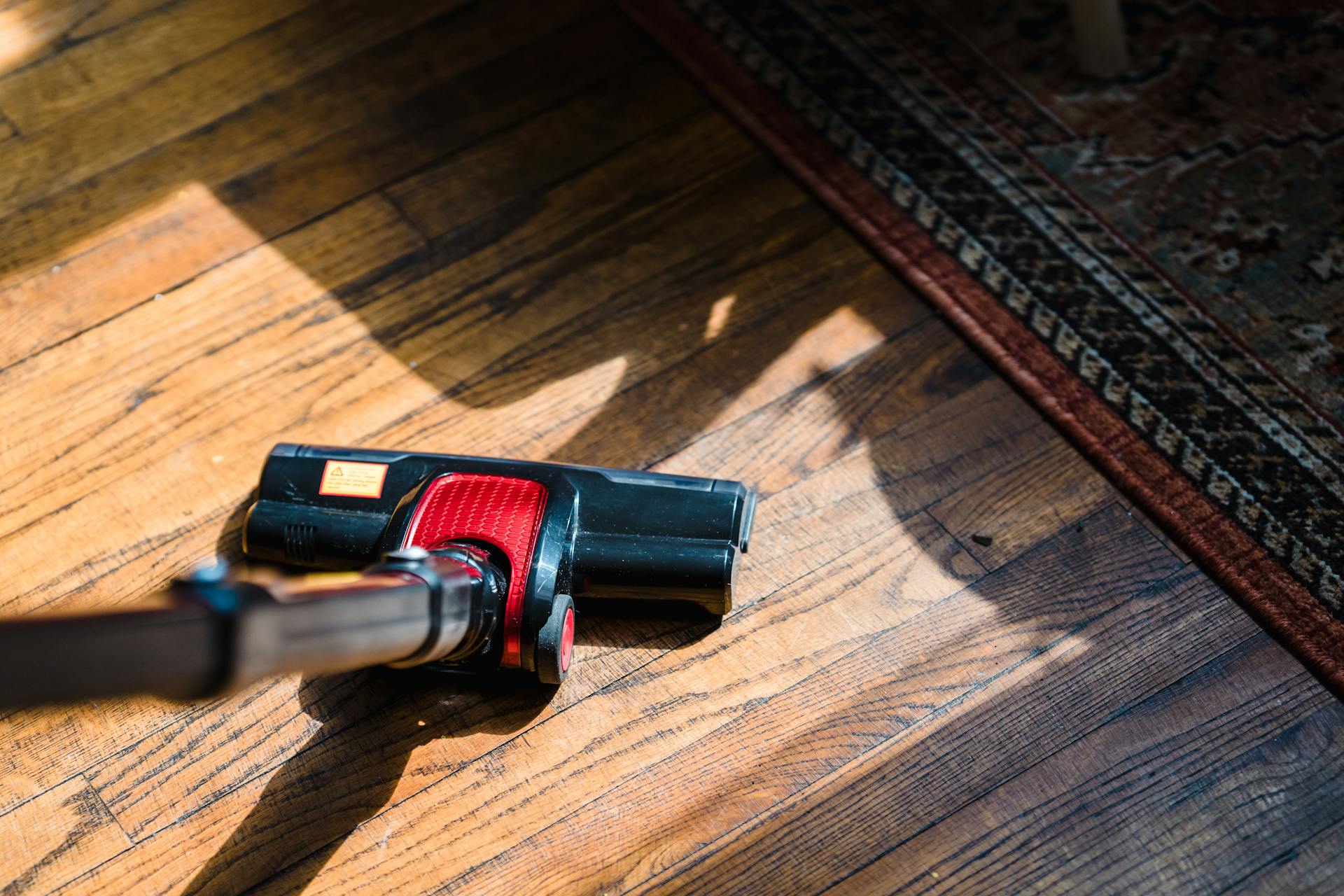 A person uses a vacuum to clean the floor.