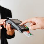A cashier holds a payment terminal, which a customer has a card inserted into to pay.