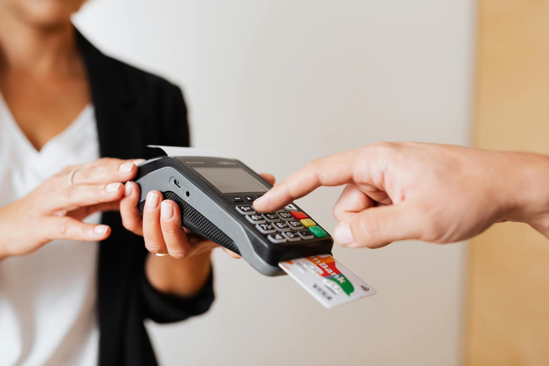 A cashier holds a payment terminal, which a customer has a card inserted into to pay.