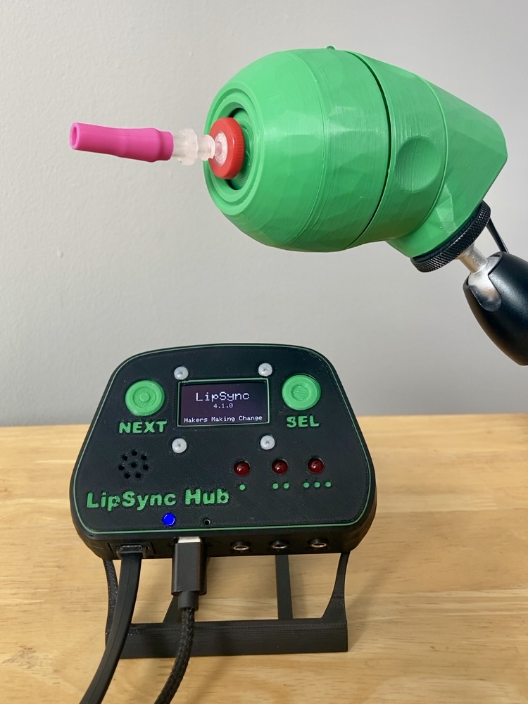A LipSync with an updated mouthstick and a LipSync Hub with the stand, displaying the text LipSync 4.1.0 Makers Making Change.