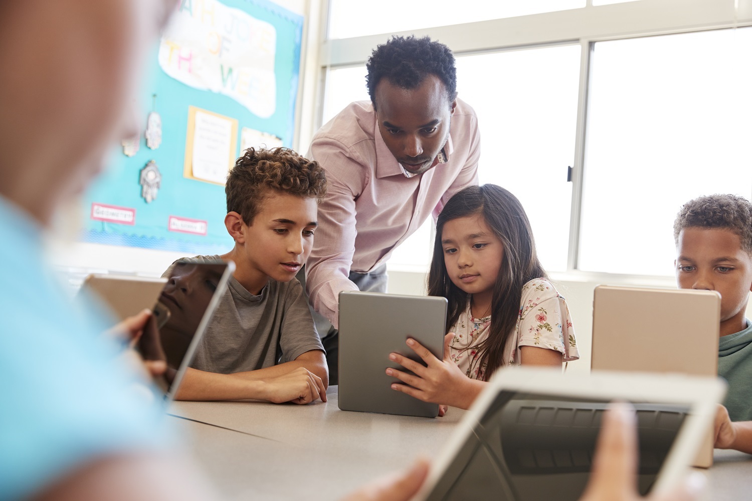 A teacher demonstrates a concept to students using a tablet.