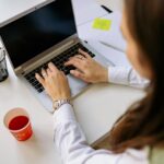 A woman types on a laptop.