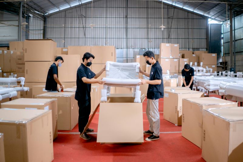 Workers packing furniture into boxes