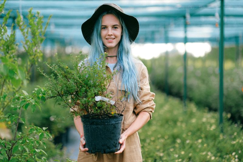 A woman holding a plant in a nursery