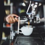 A person pours a cup of coffee from a machine.