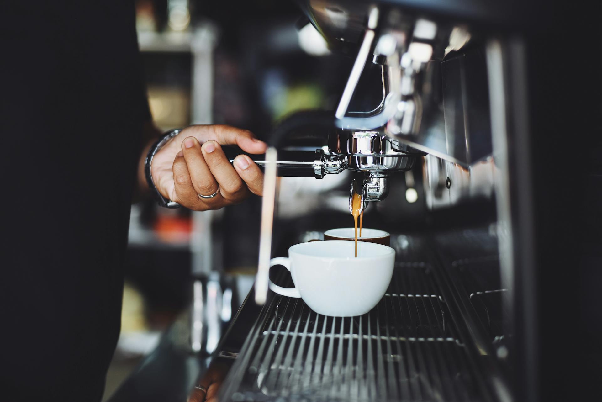 A person pours a cup of coffee from a machine.
