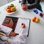 A person in a lab coat goes over a meal plan with a client.