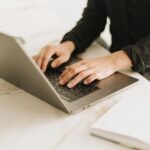 A woman types on a laptop.
