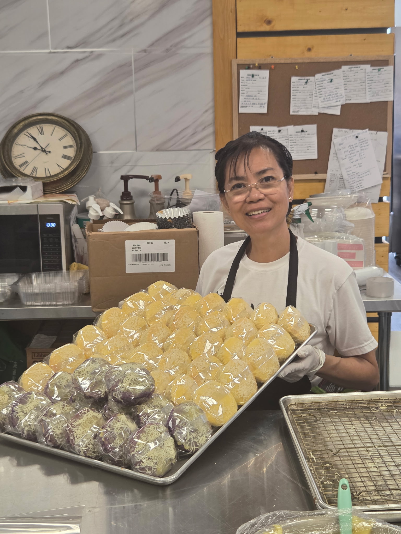 Maria holds a tray of baked goods at her workplace.