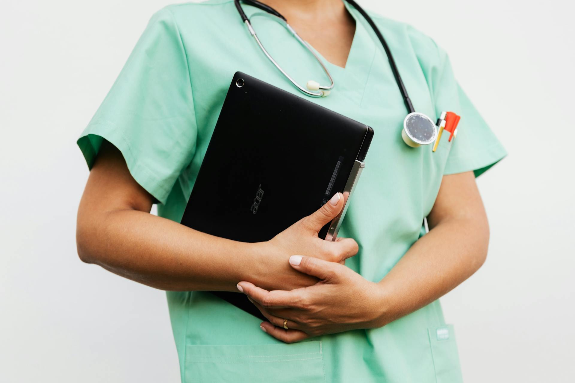 A nurse wearing scrubs and a stethoscope carries a file.