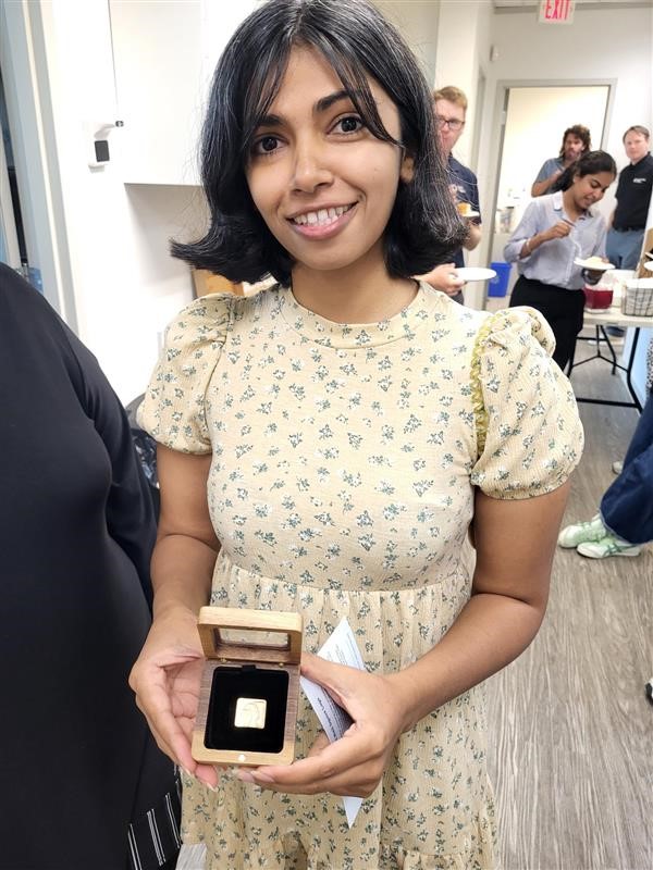 Khatidja holding a golden Neil Squire pin.