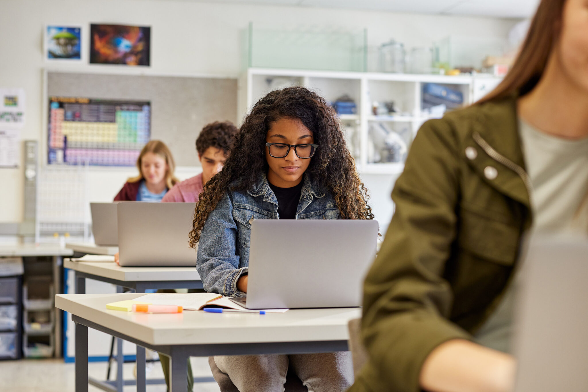 A woman in a classroom goes on laptop.