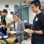 A woman smiles as she gets a plate of food.