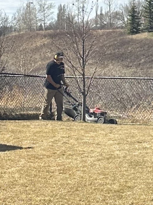 Kristian mowing a lawn at his new job.