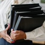 A woman carries binders.