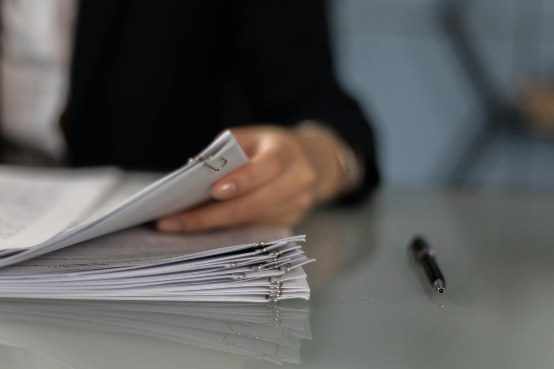 A person goes through paperwork on their desk.
