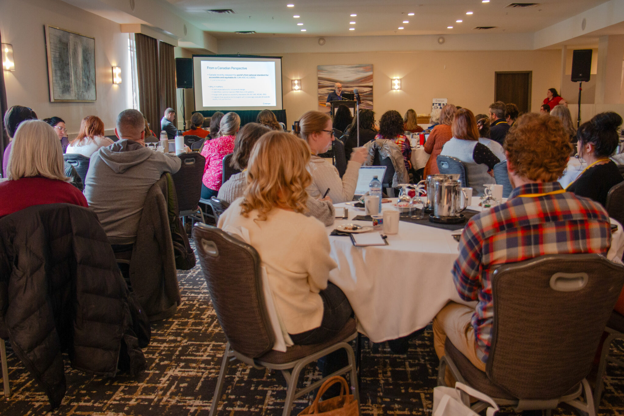 A large crowd watches a presentation by Charles Levasseur.