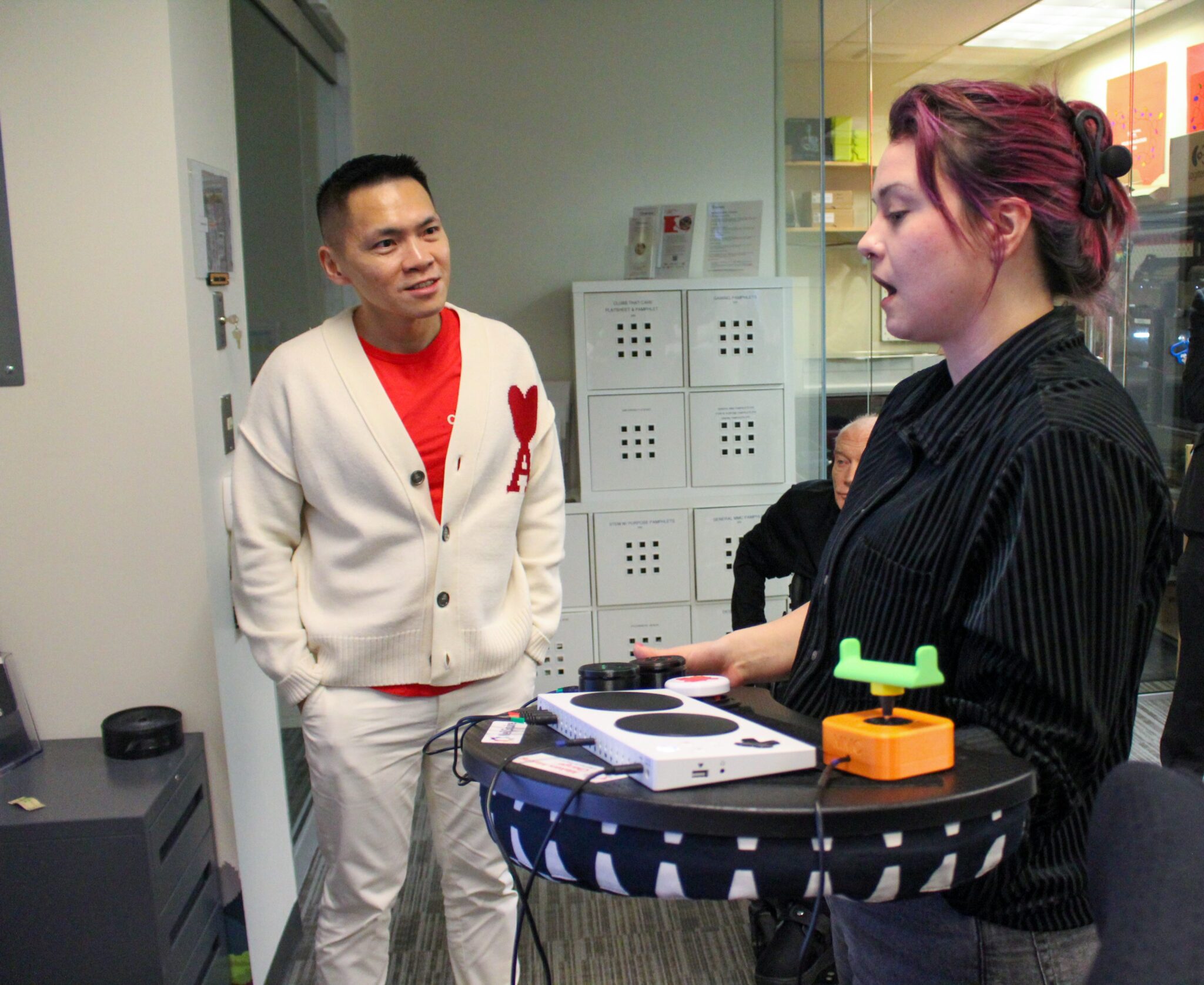 MMC BC Outreach & Operations Coordinator Kris Stirling demonstrates an adaptive controller for adaptive gaming to MP Wade Chang.