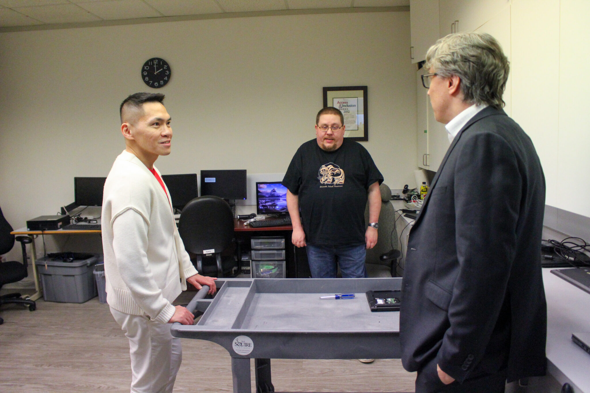 MP Wade Chang, Director of Innovation Chad Leaman, and Computer Refurbishing volunteer Matthew discuss our programs.