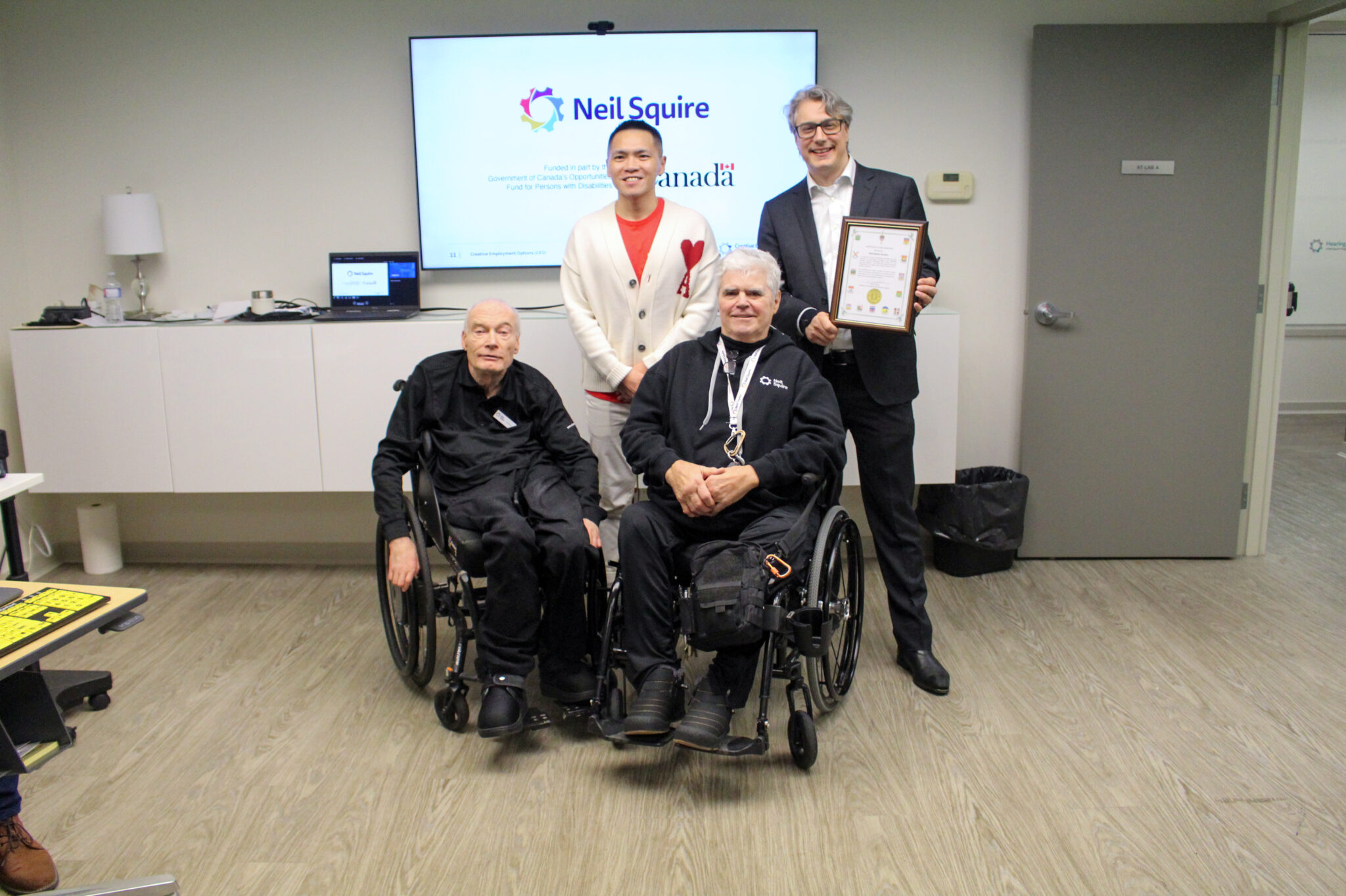 MP Wade Chang, Director of Innovation Chad Leaman, Executive Director Gary Birch, and National Operations Manager Greg Pyc pose with the certificate of recognition.