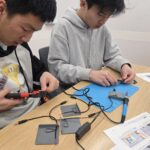 Two Cybertronic Penguinz club members building switches at a build event.