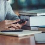 A person uses a smartphone while studying at a library.