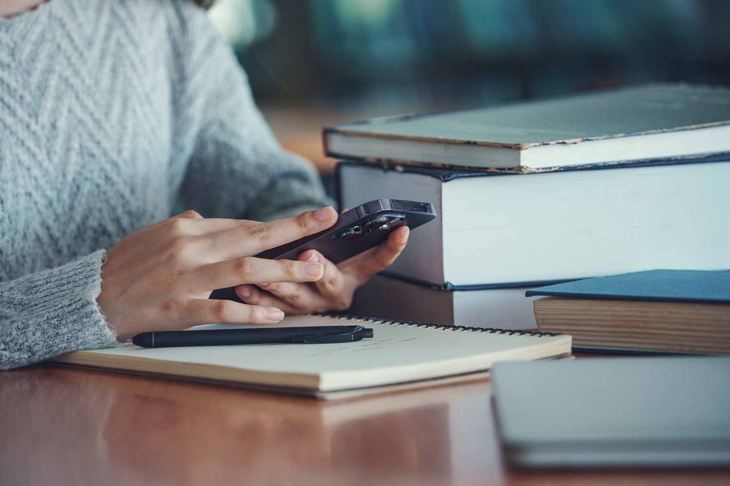 A person uses a smartphone while studying at a library.