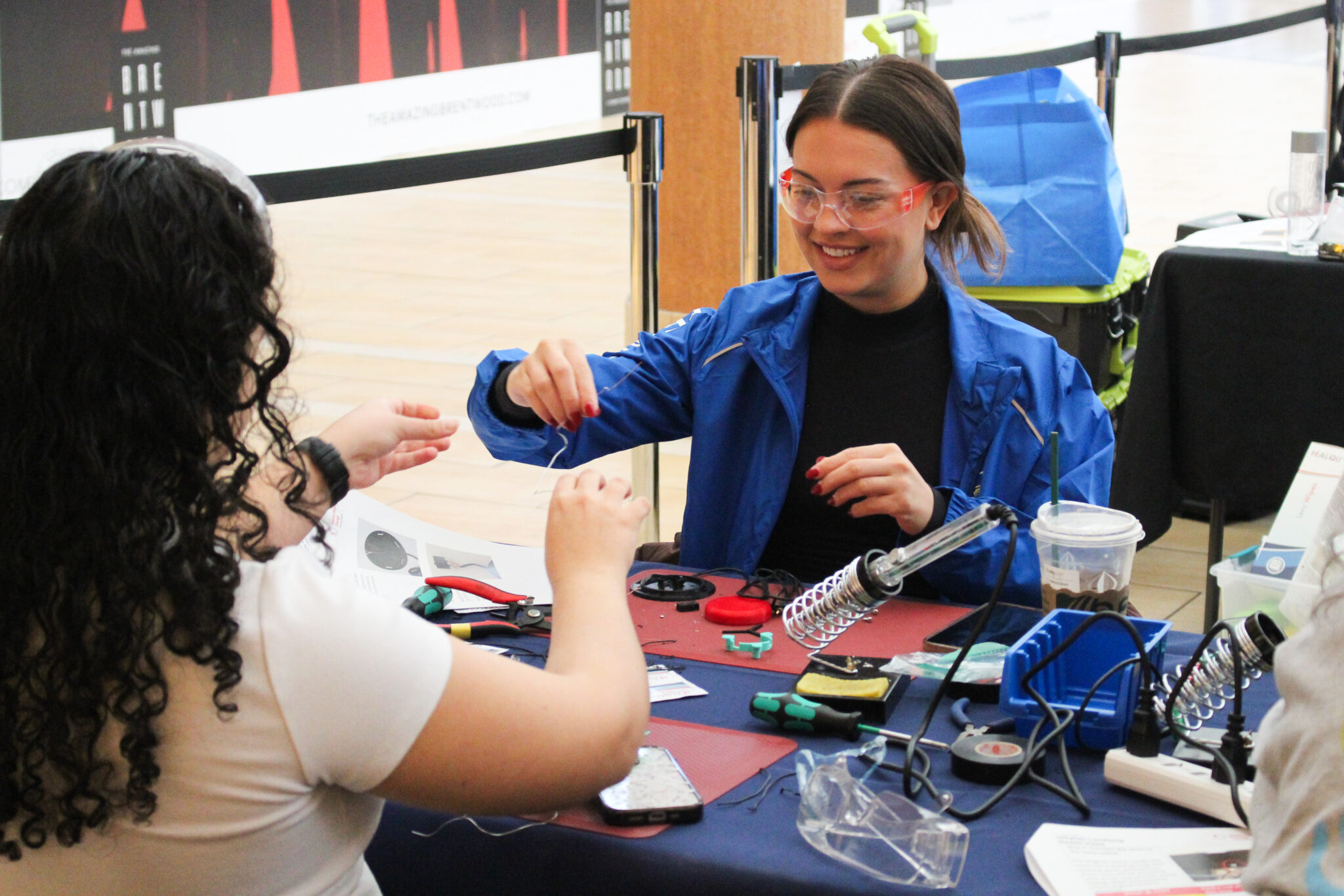 Two volunteers work on a device during a build event.