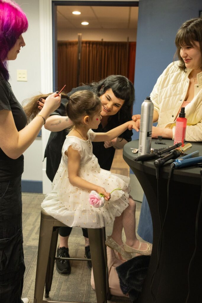 Hair stylists do hair for a kid at the event.