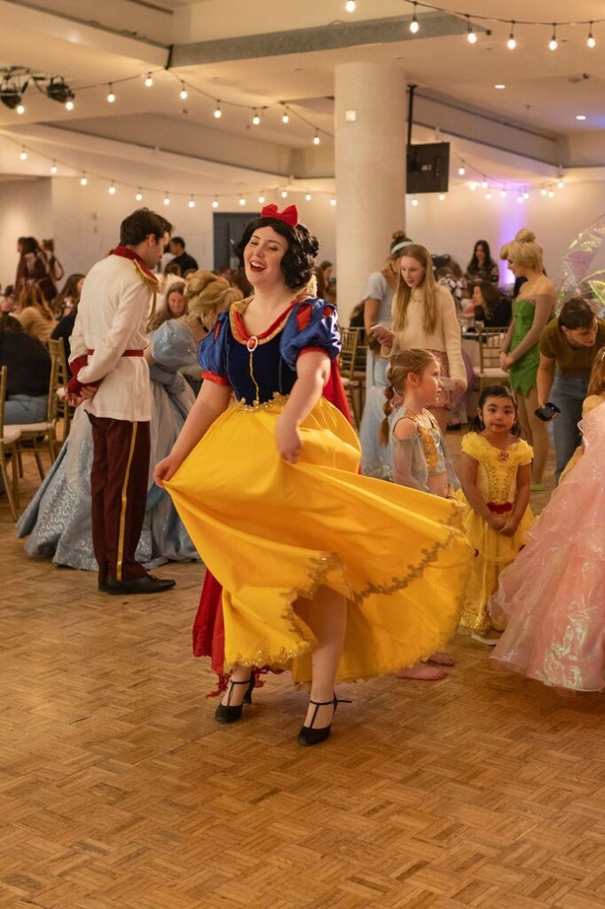 A performer dressed as Snow White smiles and dances.
