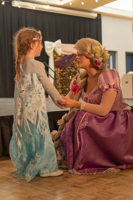 A princess performer talks to a kid dressed as a princess.