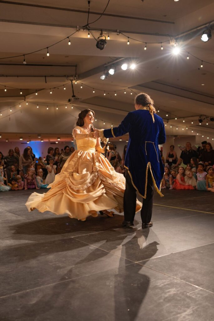 Performers dressed as beauty and the beast dance on stage.
