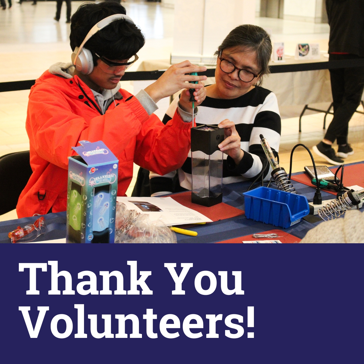 Two volunteers work on adapting a toy at a build event. Text: Thank you volunteers!
