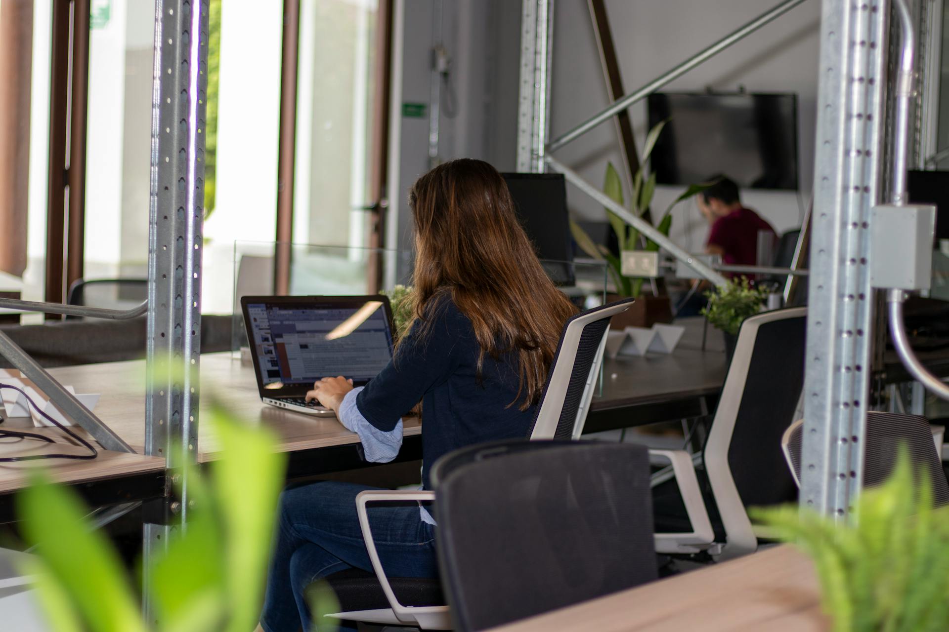 A woman works on a laptop in an office.