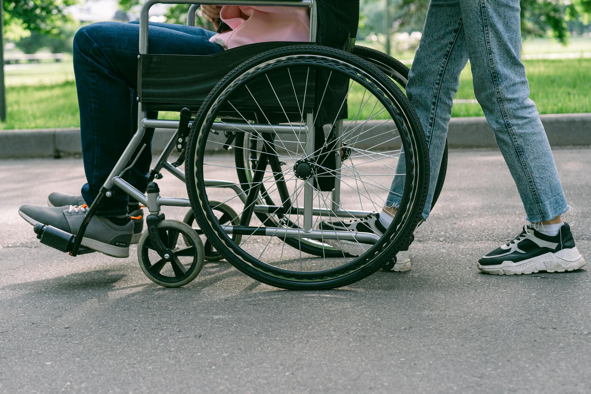 A caregiver pushes a person in a wheelchair.