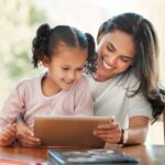 A mother watches something on a tablet with a child.