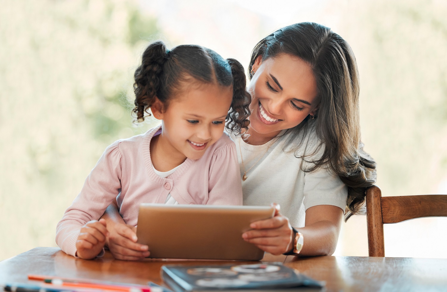 A mother watches something on a tablet with a child.