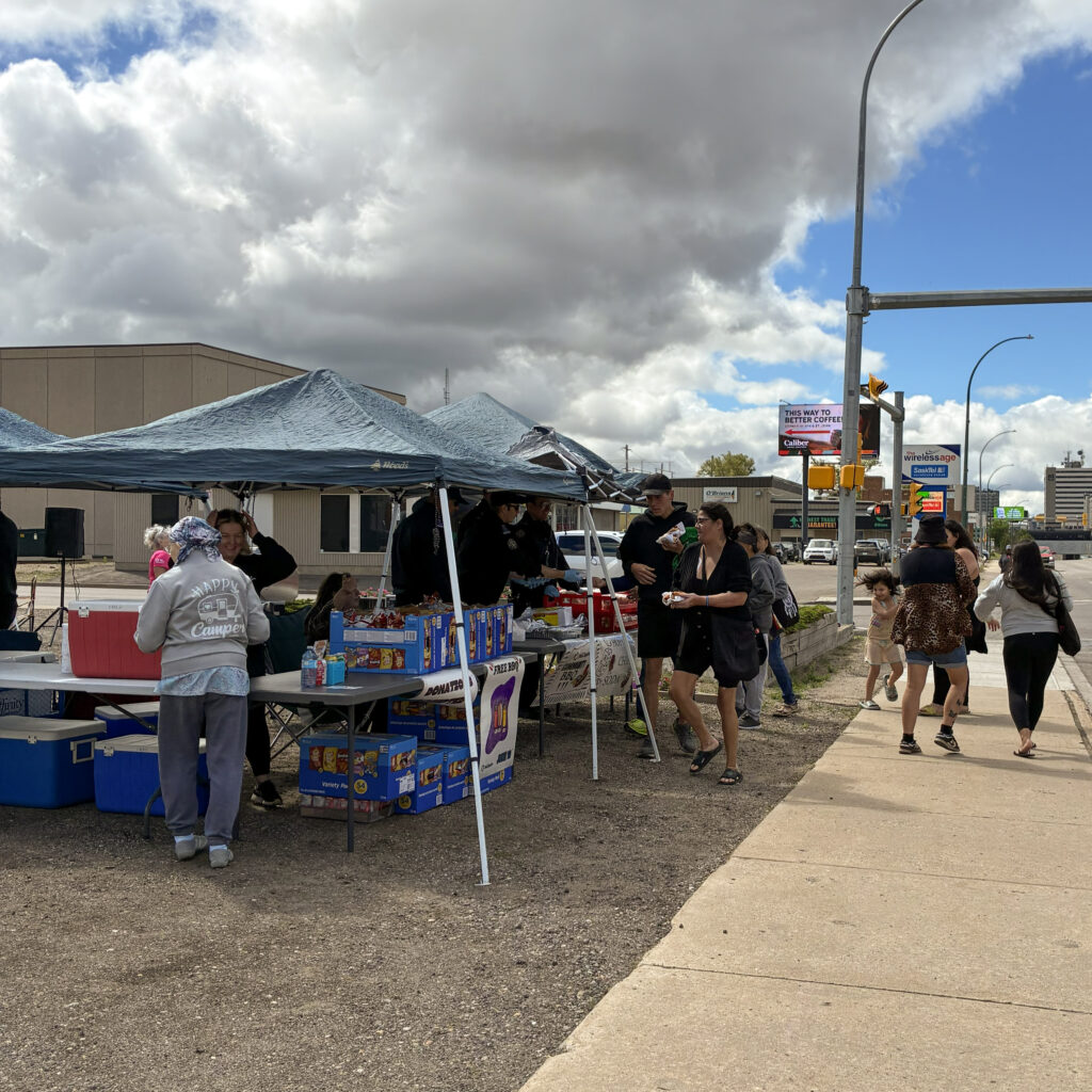 People line up for hot dogs at the barbecue.