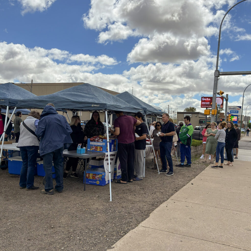 People line up for hot dogs at the barbecue.