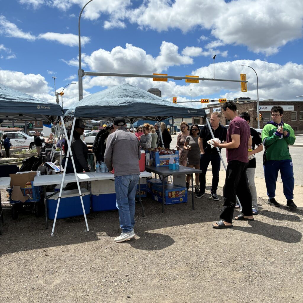 People line up for hot dogs at the barbecue.