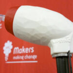 The LipSync Classic in front of a backdrop with the old Makers Making Change logo.