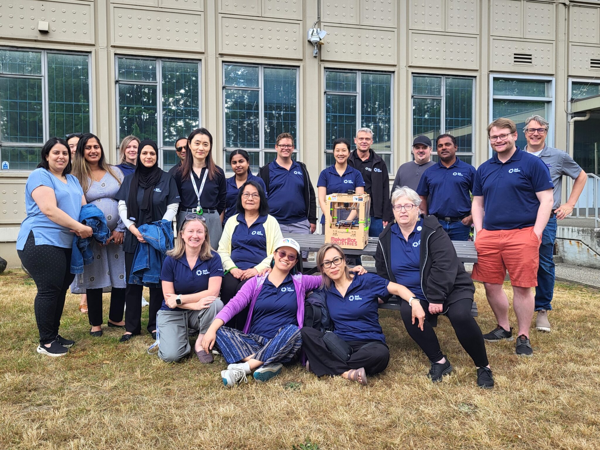 Current Neil Squire Burnaby staff outside our old office, posing with a 3D printer with a wooden case.