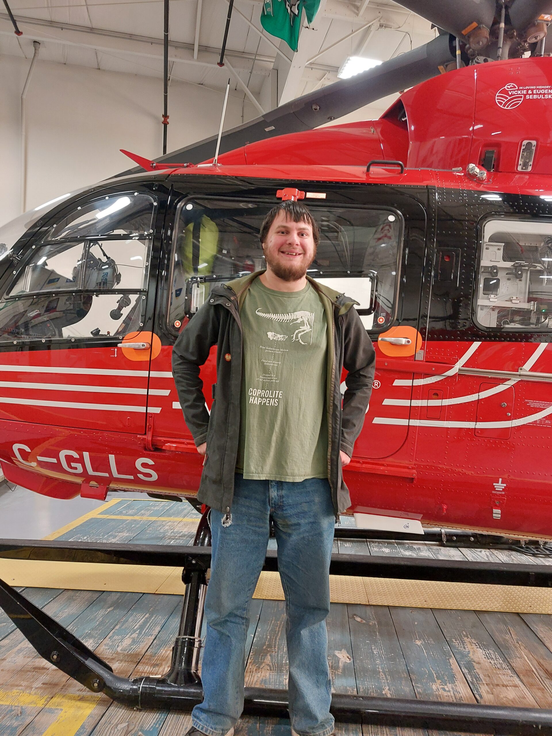 Karl standing smiling in front of the red STARS helicopter inside the hangar.
