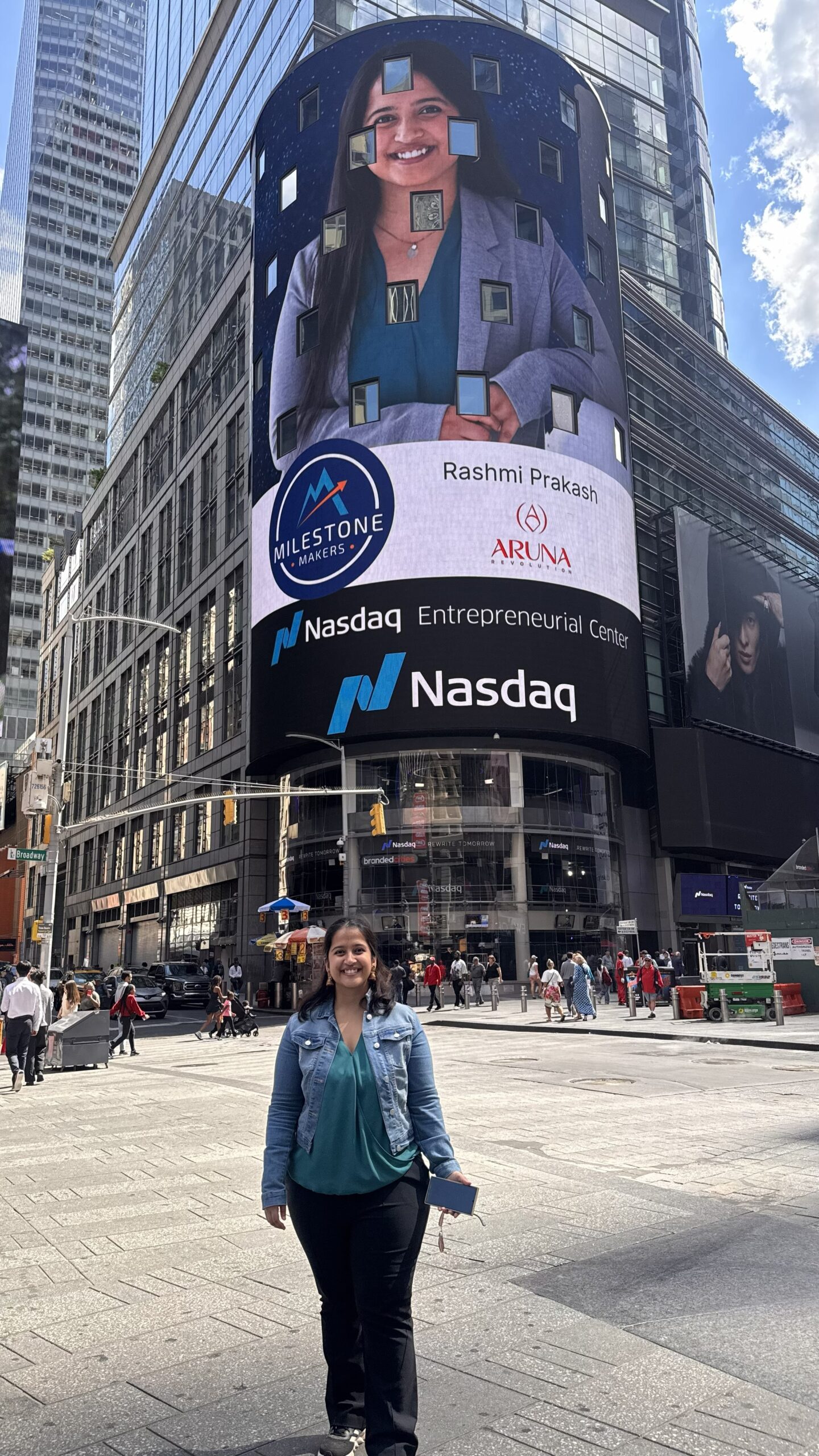 Rashmi standing in front of the Nasdaq Entrepreneurial Center, which has a large image of Rashmi on the building, advertising her as a milestone maker for her startup Aruna Revolution.