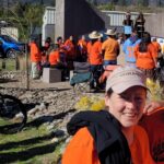 Mindy, wearing an orange shirt, standing in front of the Syilx Indian Residential School (SIRS) Monument.