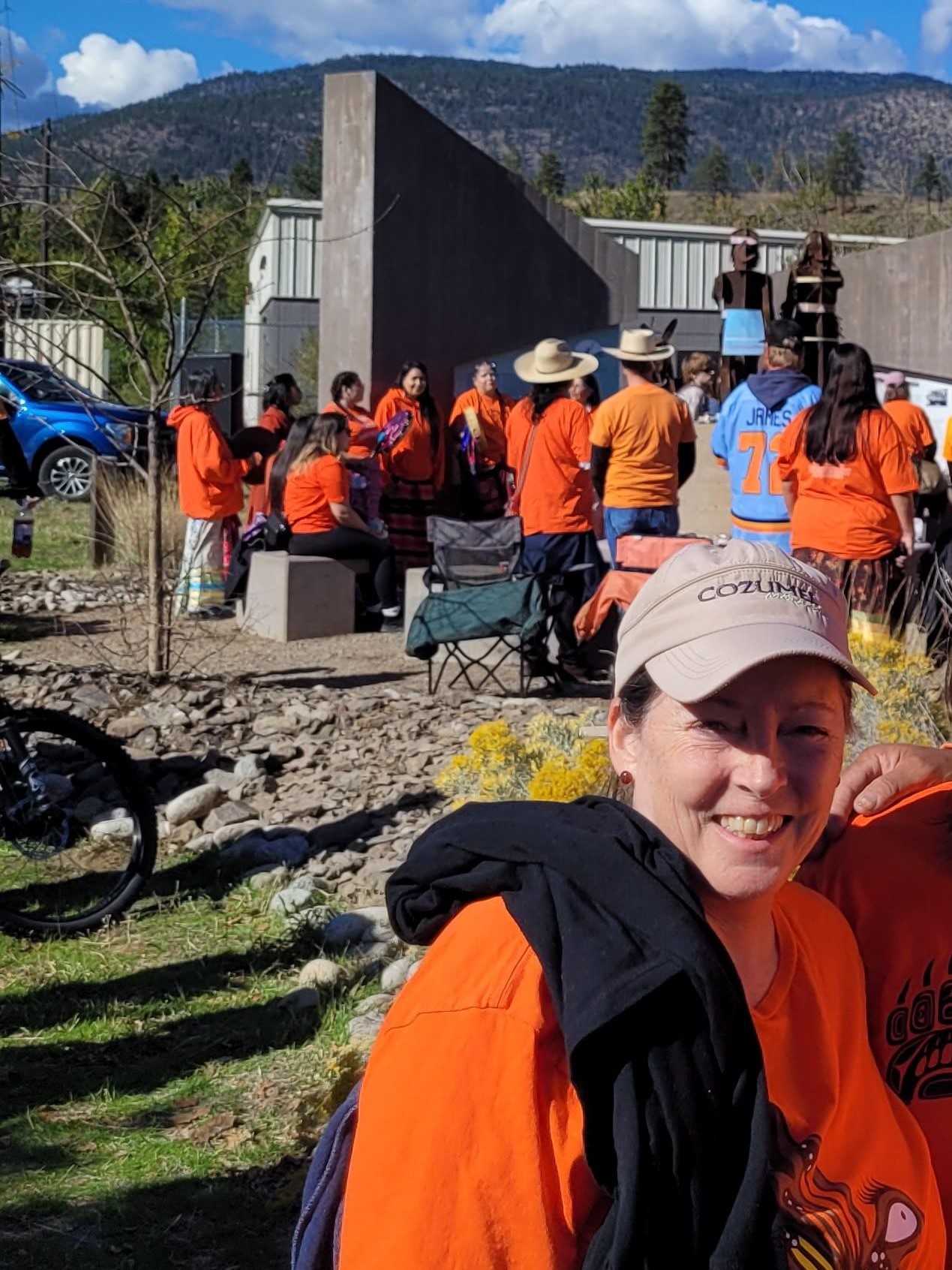 Mindy, wearing an orange shirt, standing in front of the Syilx Indian Residential School (SIRS) Monument.