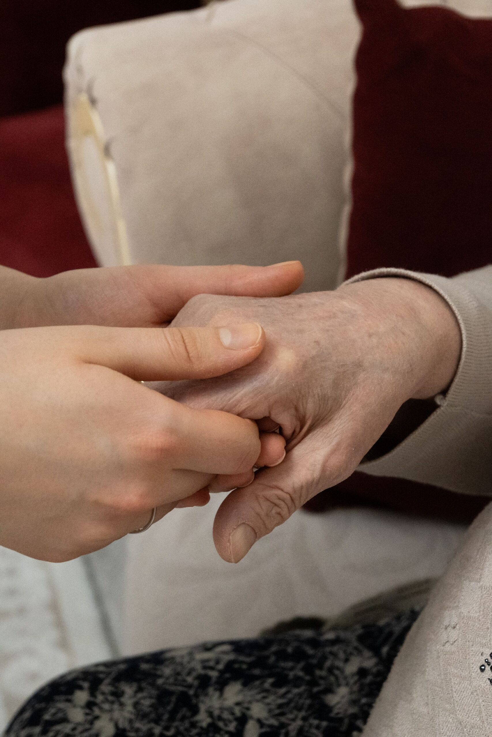 A younger person gently holding the hand of an elderly individual, conveying care and support.
